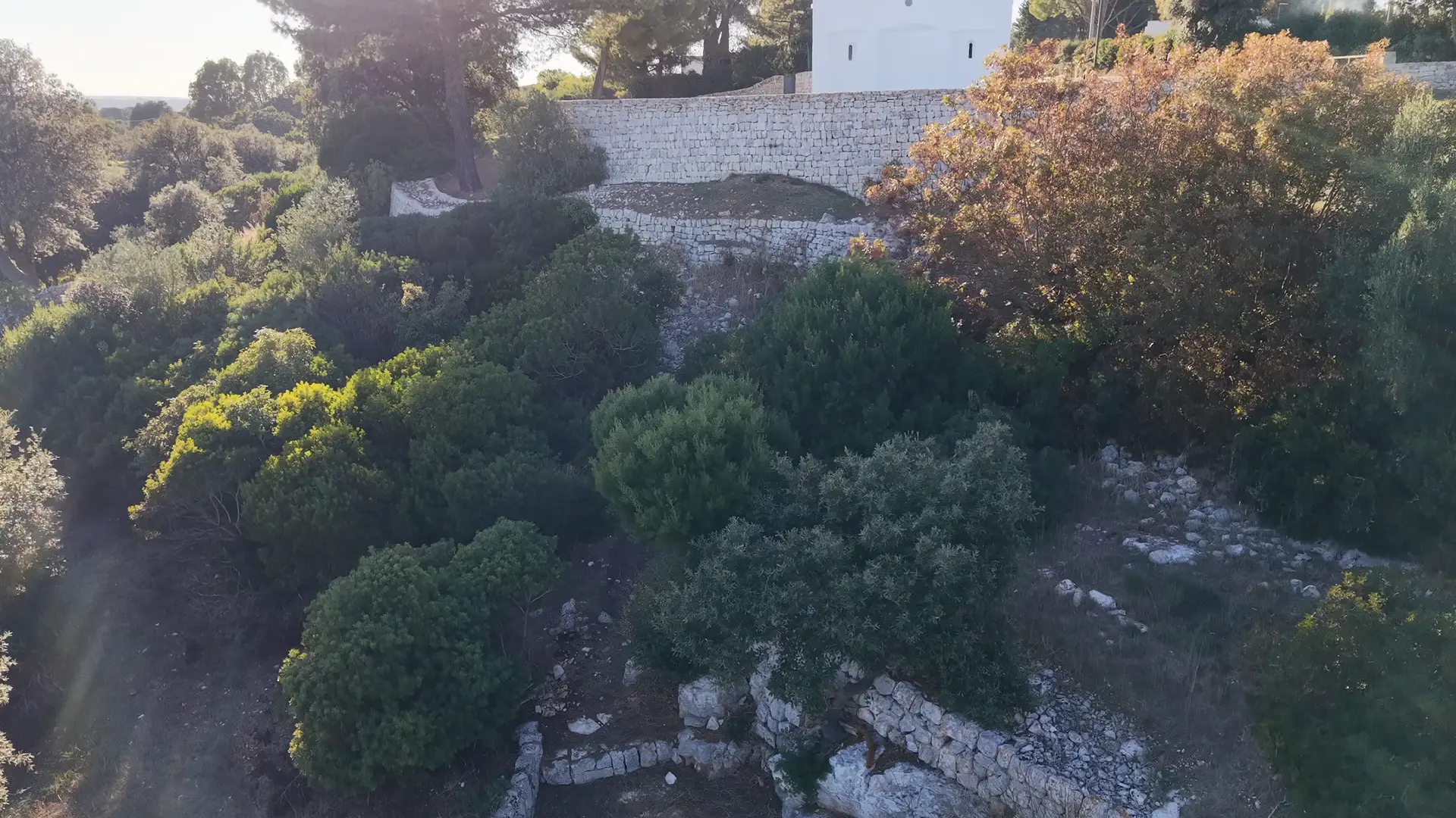 Il drone sale dalle rocce del pendio e scopre la chiesa bianca sul suo piazzale rotondo.